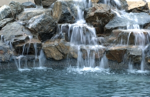 Photo of waterfall in pool professionally constructed by OC California Amaziing Pools and Spa Service